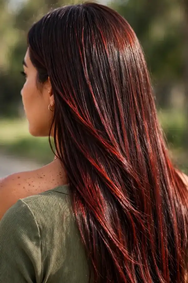 Classic all-over cherry cola brunette hair color on a woman with long glossy hair