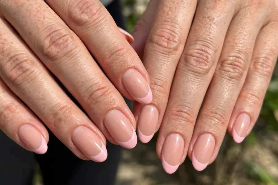 Blush French tip nails on real hands with soft pink tips