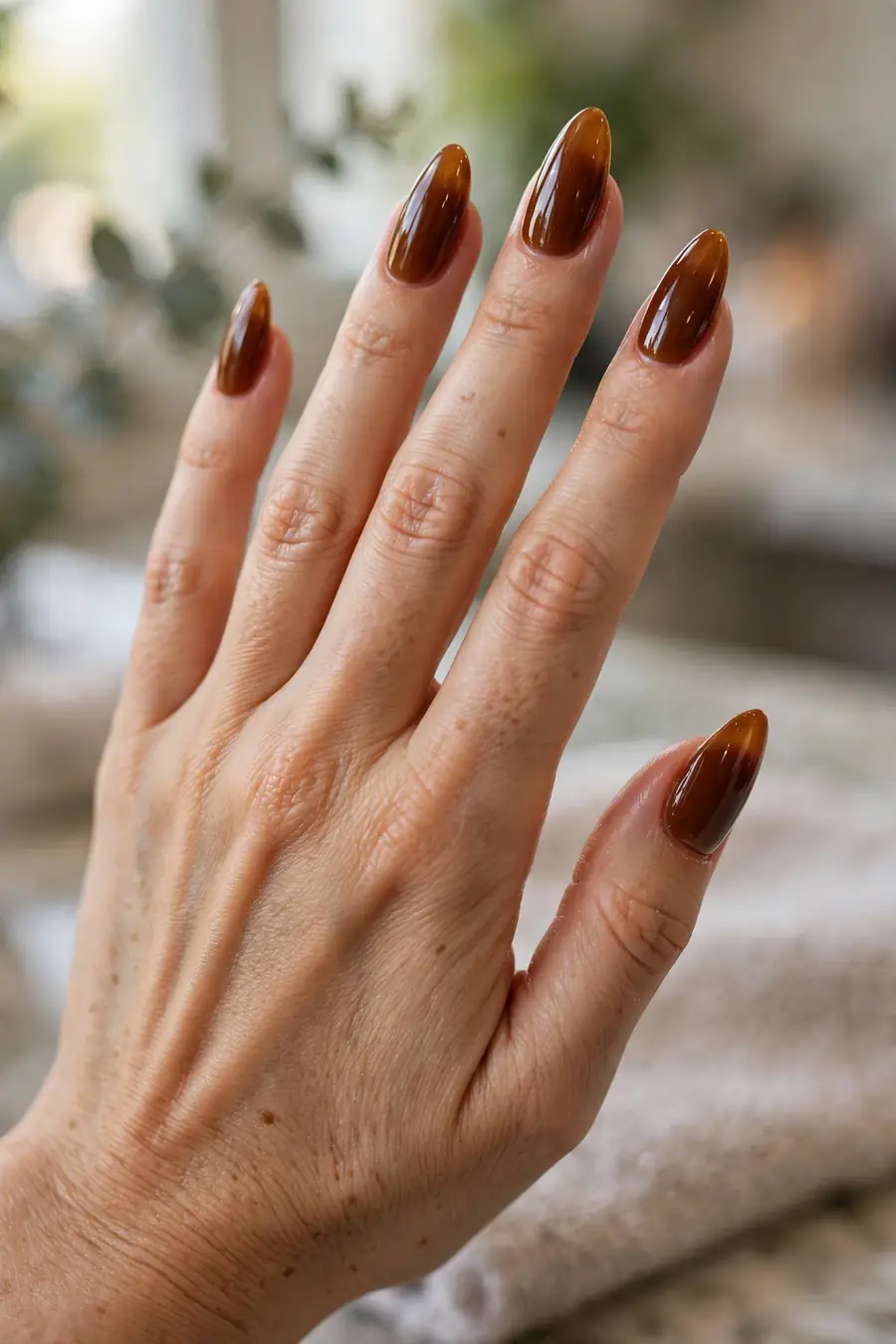 Deep toffee caramel nude nails on long almond nails with a rich glossy finish
