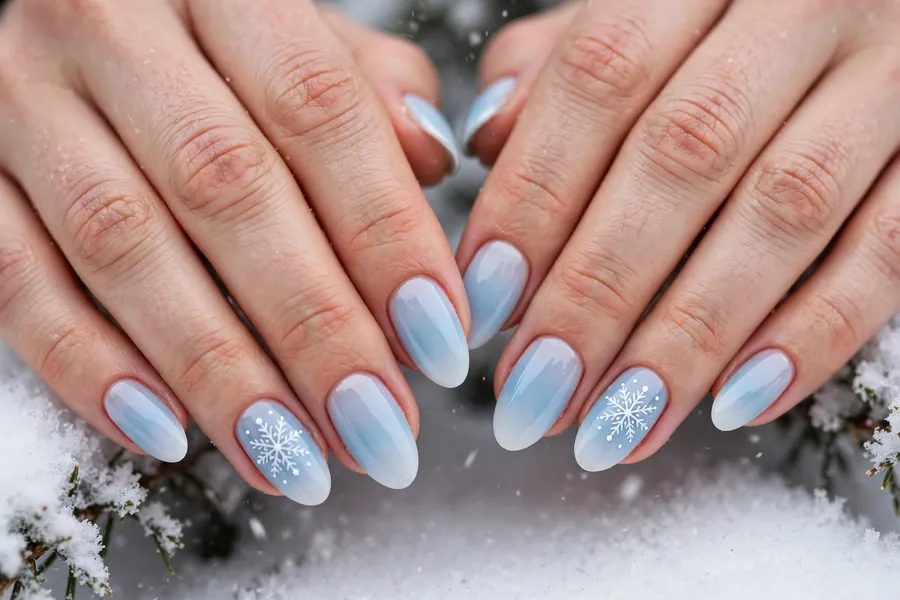 Icy blue ombre nails fading to white with white snowflake nail art on real hands