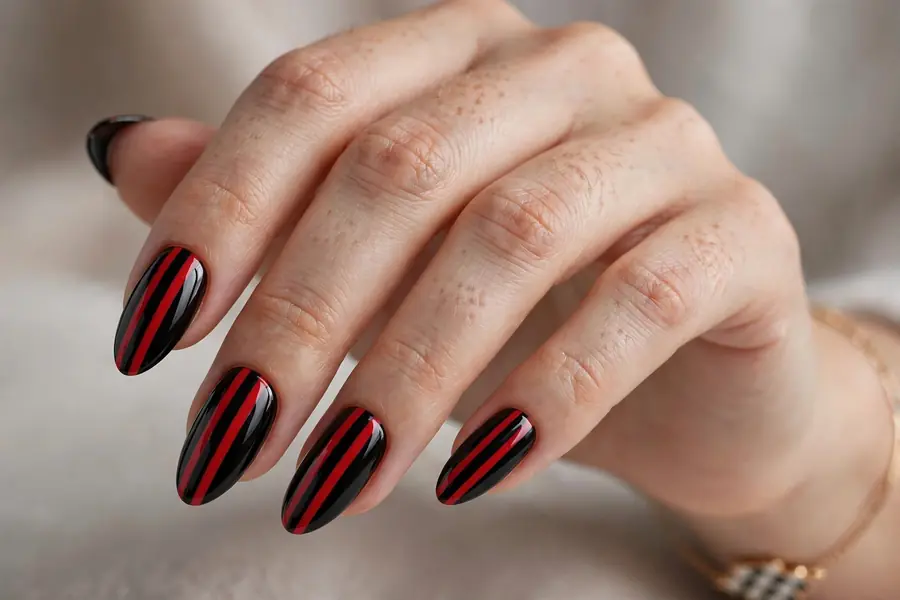 Red racing double stripes on black almond nails, real hands