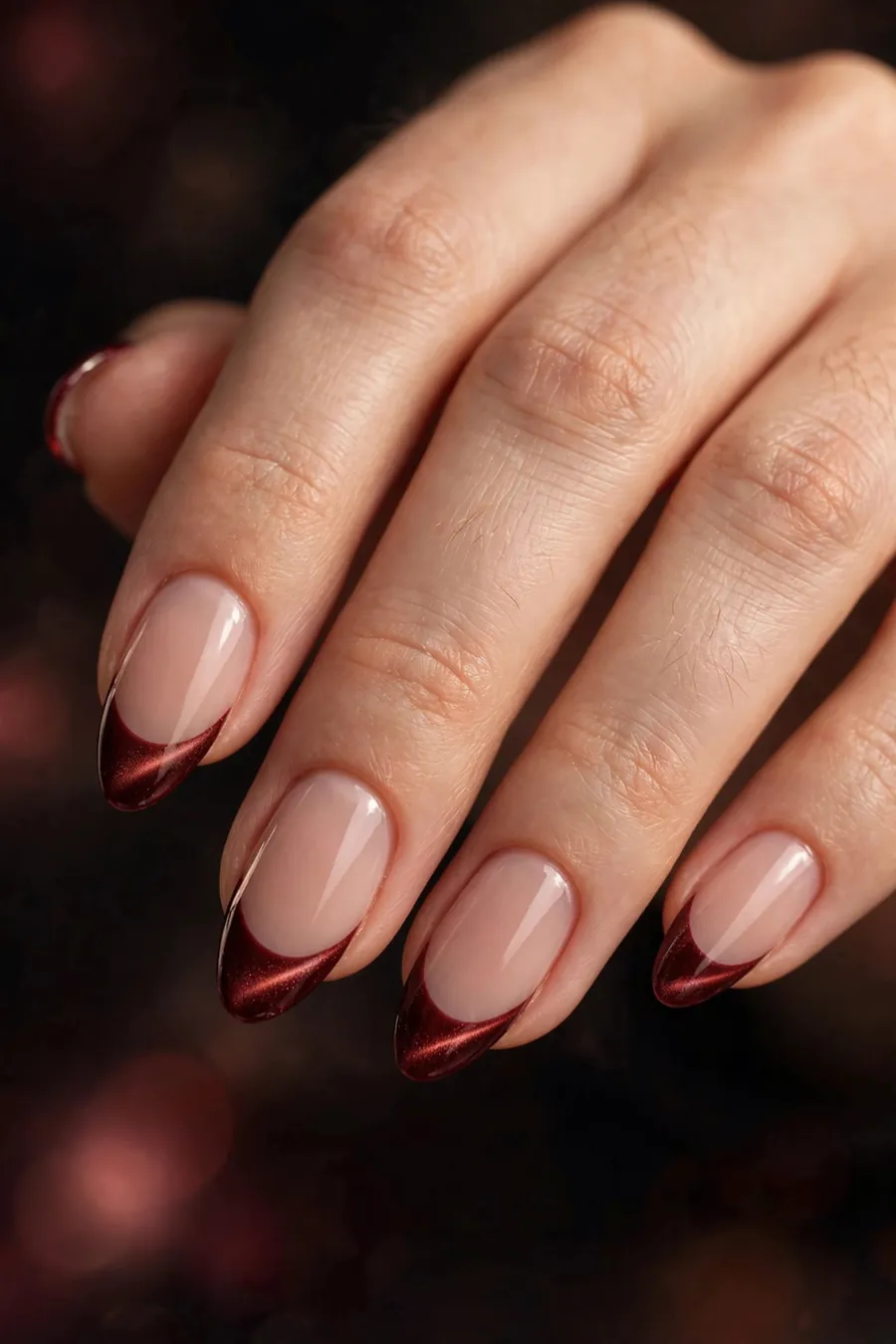Dark red cat eye French tip nails on a sheer nude base