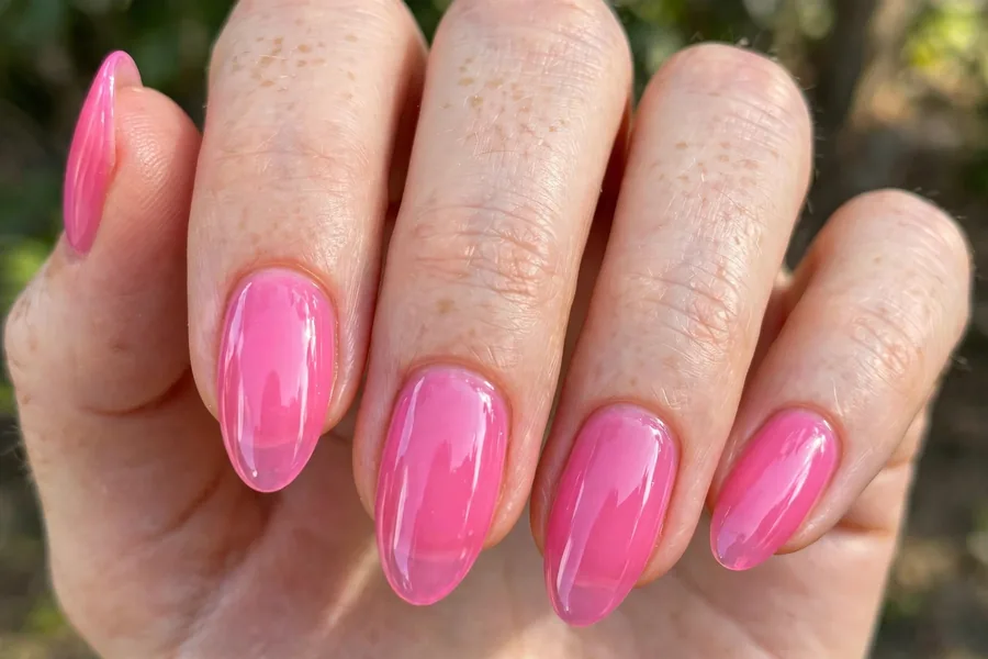Real hand with bright pink jelly lip gloss nails, translucent glossy finish