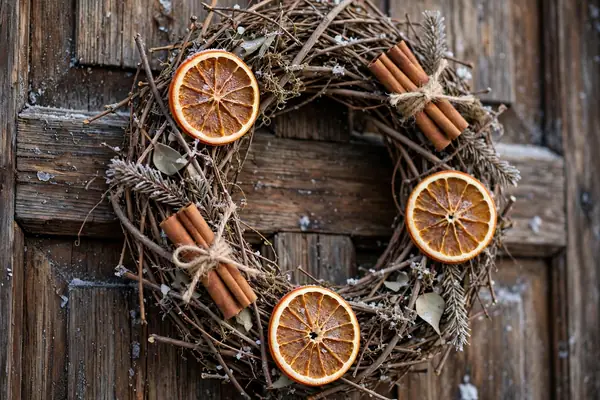 Photorealistic photograph of a rustic twig wreath with dried oranges and cinnamon sticks on a wooden front door