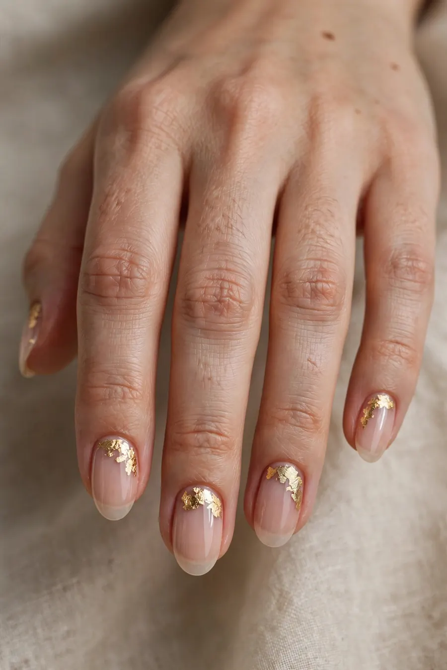Nude nails with gold leaf accents for New Year's Eve