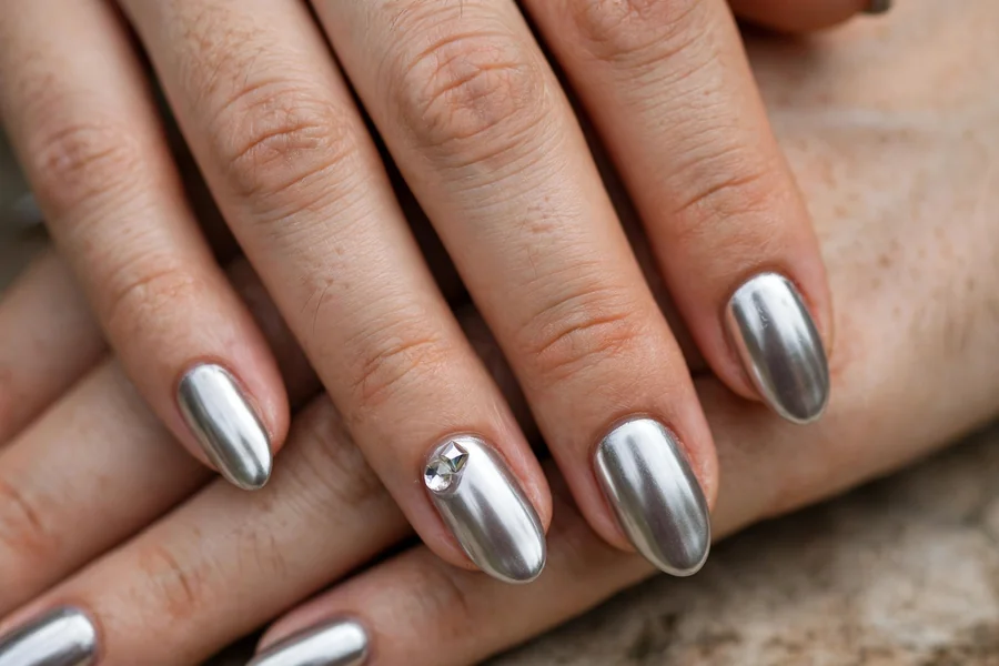 Silver chrome nails with a small crystal accent on real hands