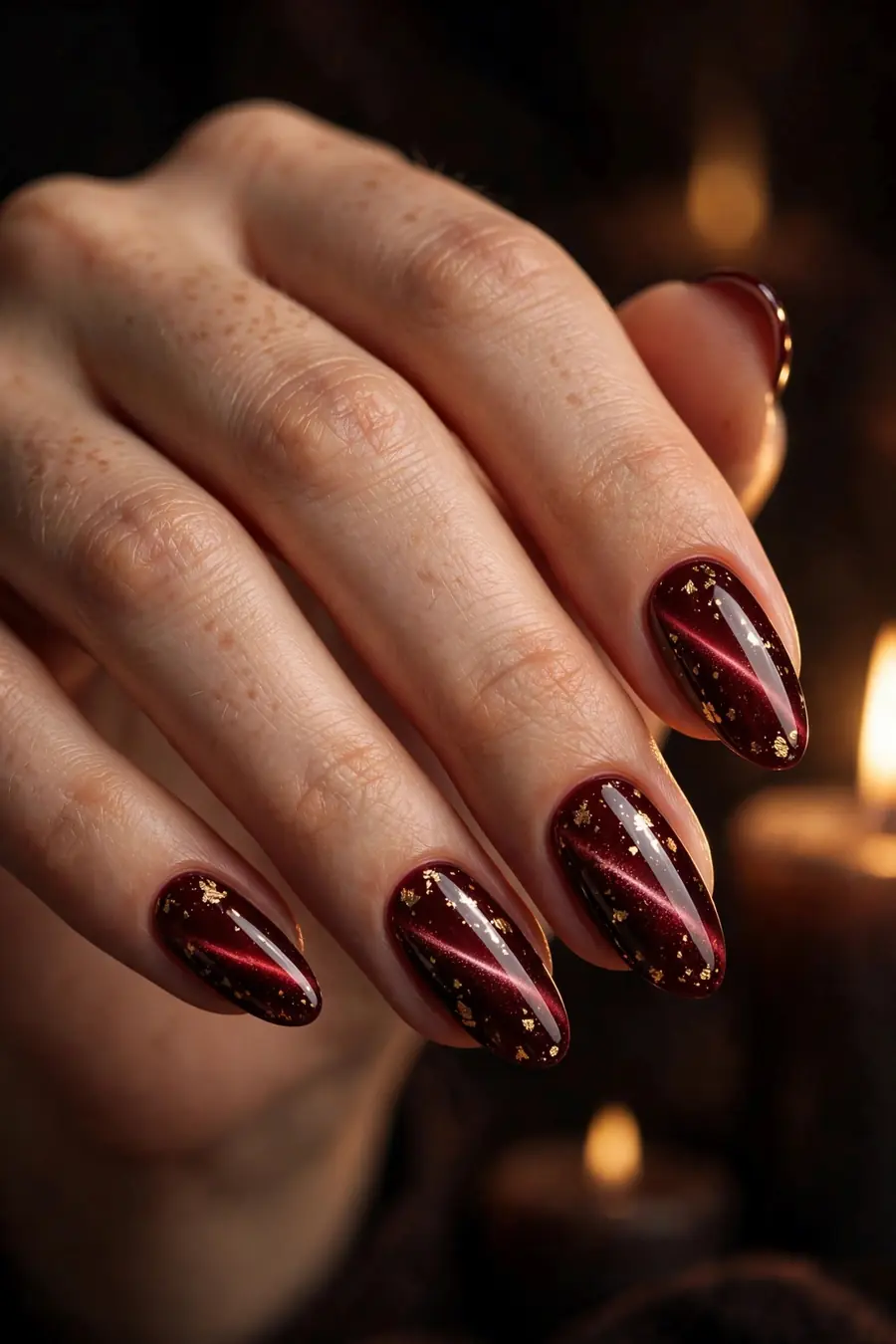 Dark red cat eye nails with gold foil flakes