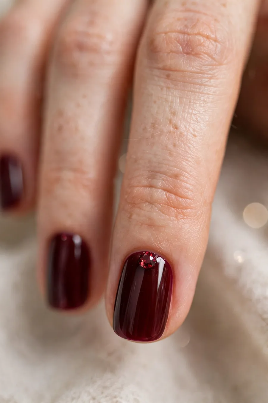 Burgundy nails with garnet rhinestone accents