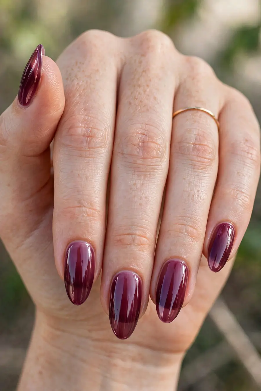 Real hand with sheer plum wine lip gloss nails, rich glossy shine