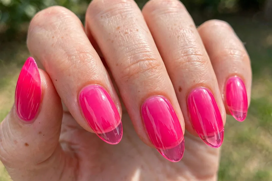 Real hand with vivid hot pink jelly lip gloss nails, high-shine finish