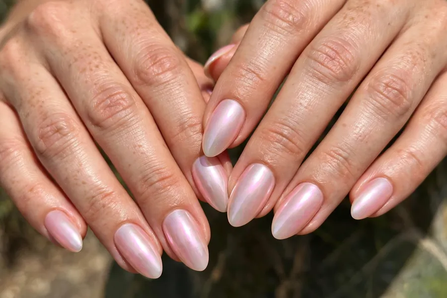 Blush pearl chrome nails on real hands with a luminous pearly pink finish