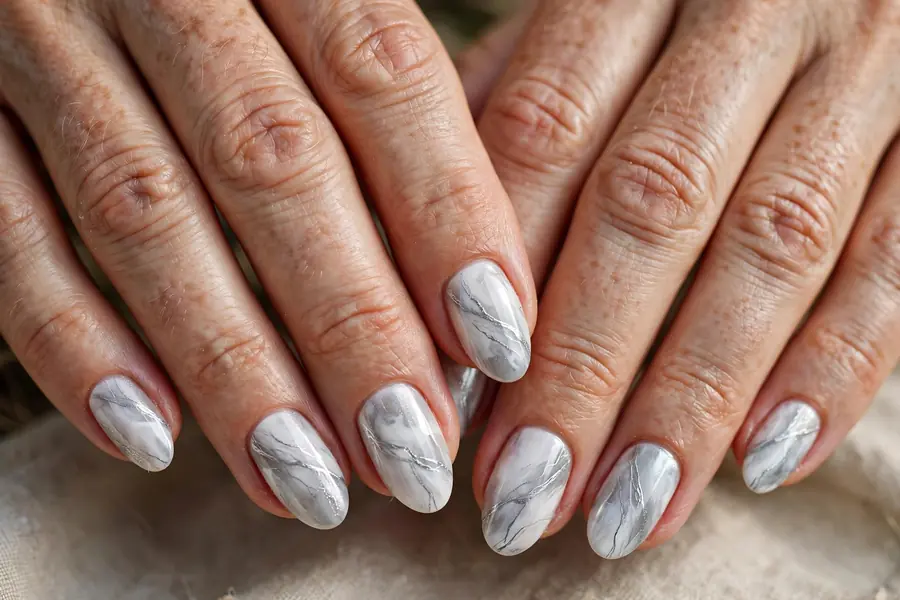 Silver and white winter marble nails on real hands against a snowy background